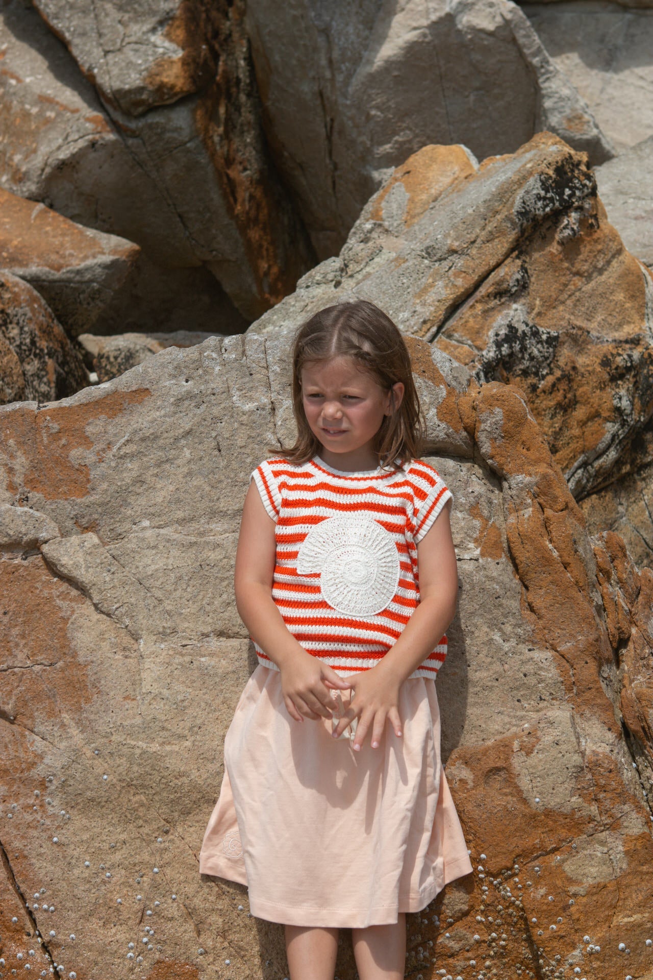 Young girl in a red and white striped vest with a crochet shell.