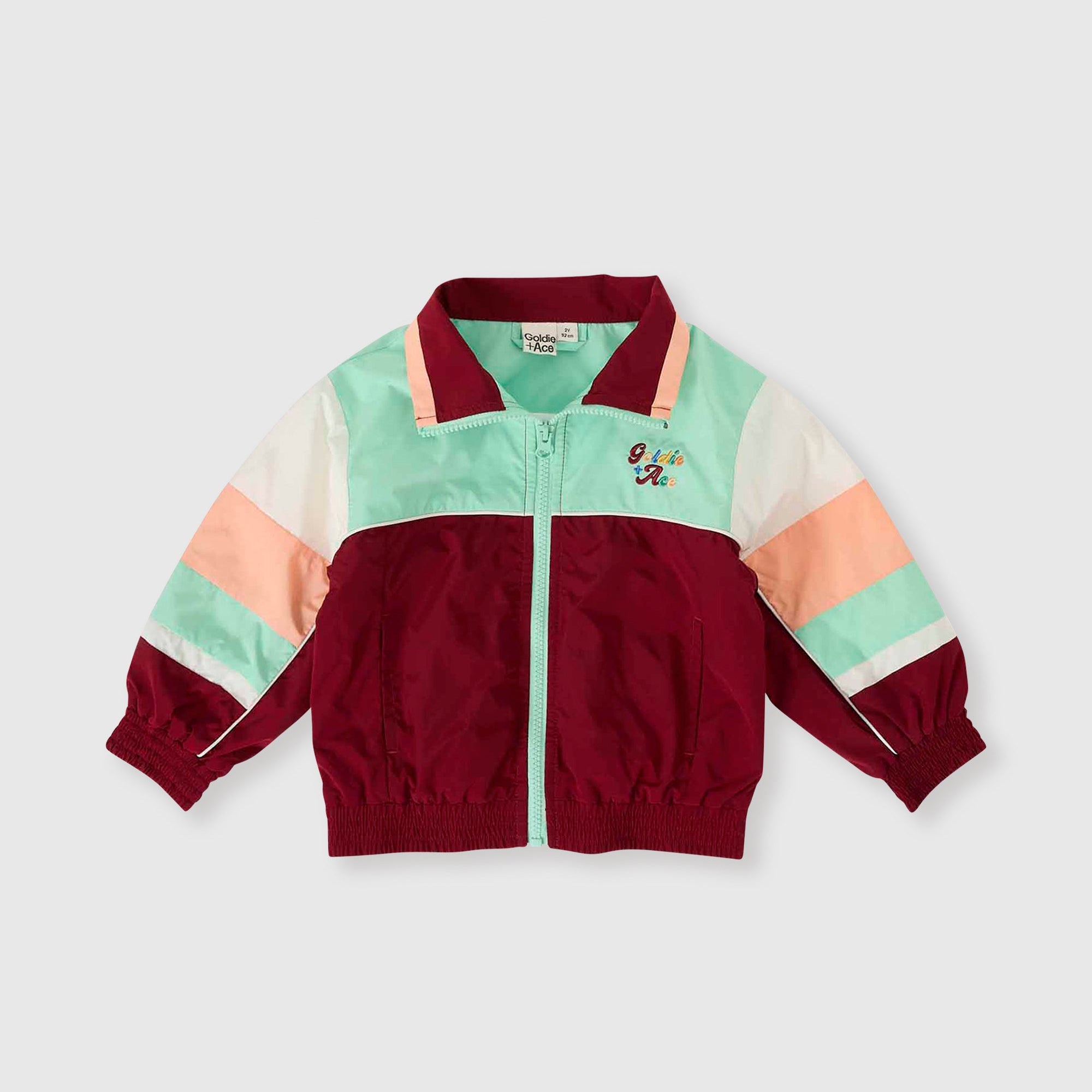 Color-blocked jacket with maroon, green, and peach sections on a light gray background