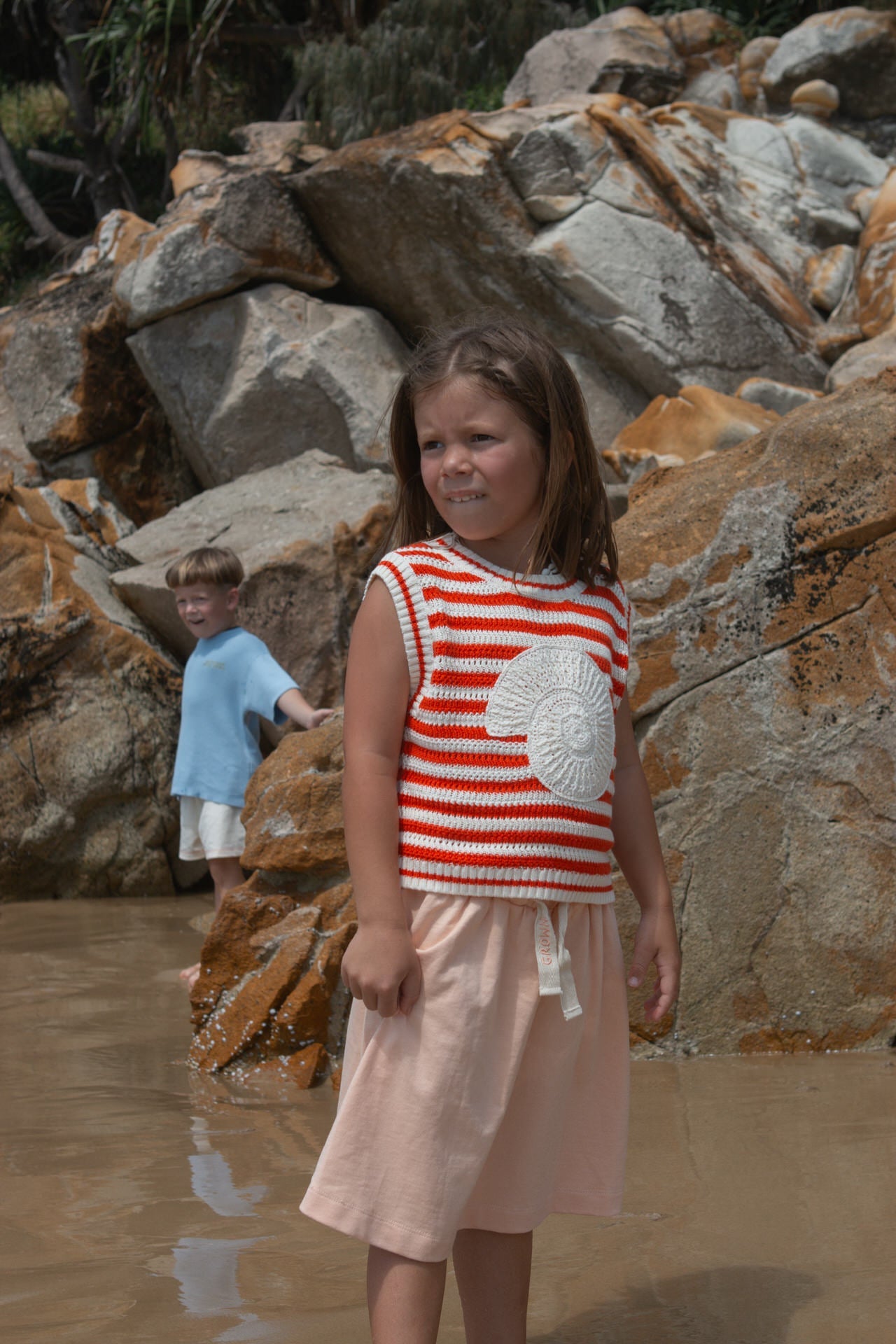 Young girl in a red and white striped vest with a crochet shell.